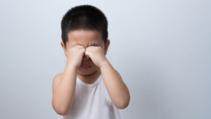 Une douleur dans l'œil de l'enfant asiatique qui se tient les yeux.