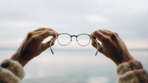 Comment améliorer son champ visuel : deux mains qui tiennent une paire de lunettes.